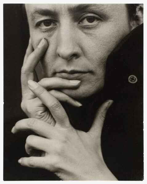 Black and white portrait photograph of Artist Georgia O’Keeffe with hand posed across her face.