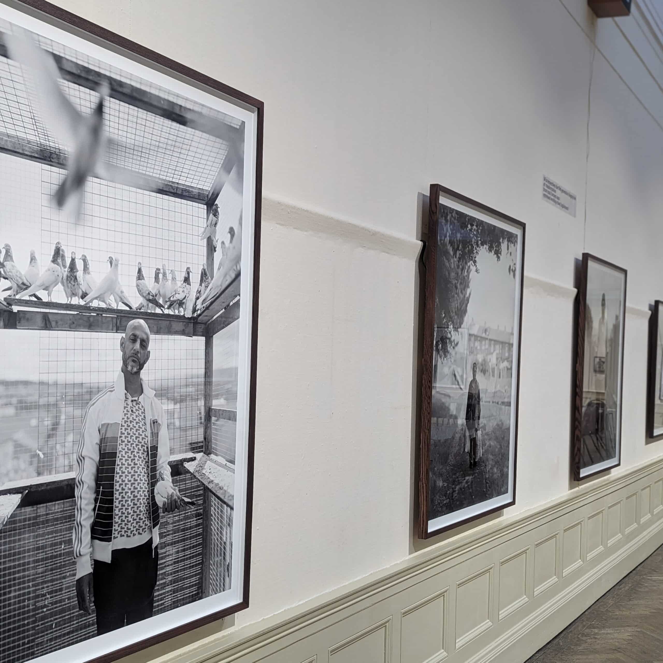 Photograph of three large black-and-white photos on wall of a gallery. From Craig Easton's exhibition Is Anybody Listening?