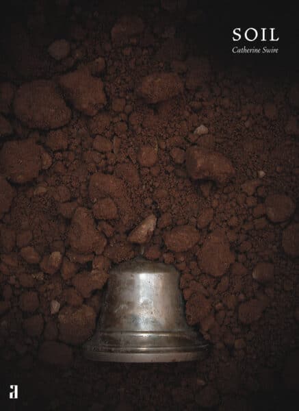 Front cover of a book called Soil by Catherine Swire, showing a metal bell half-buried vertically in soil