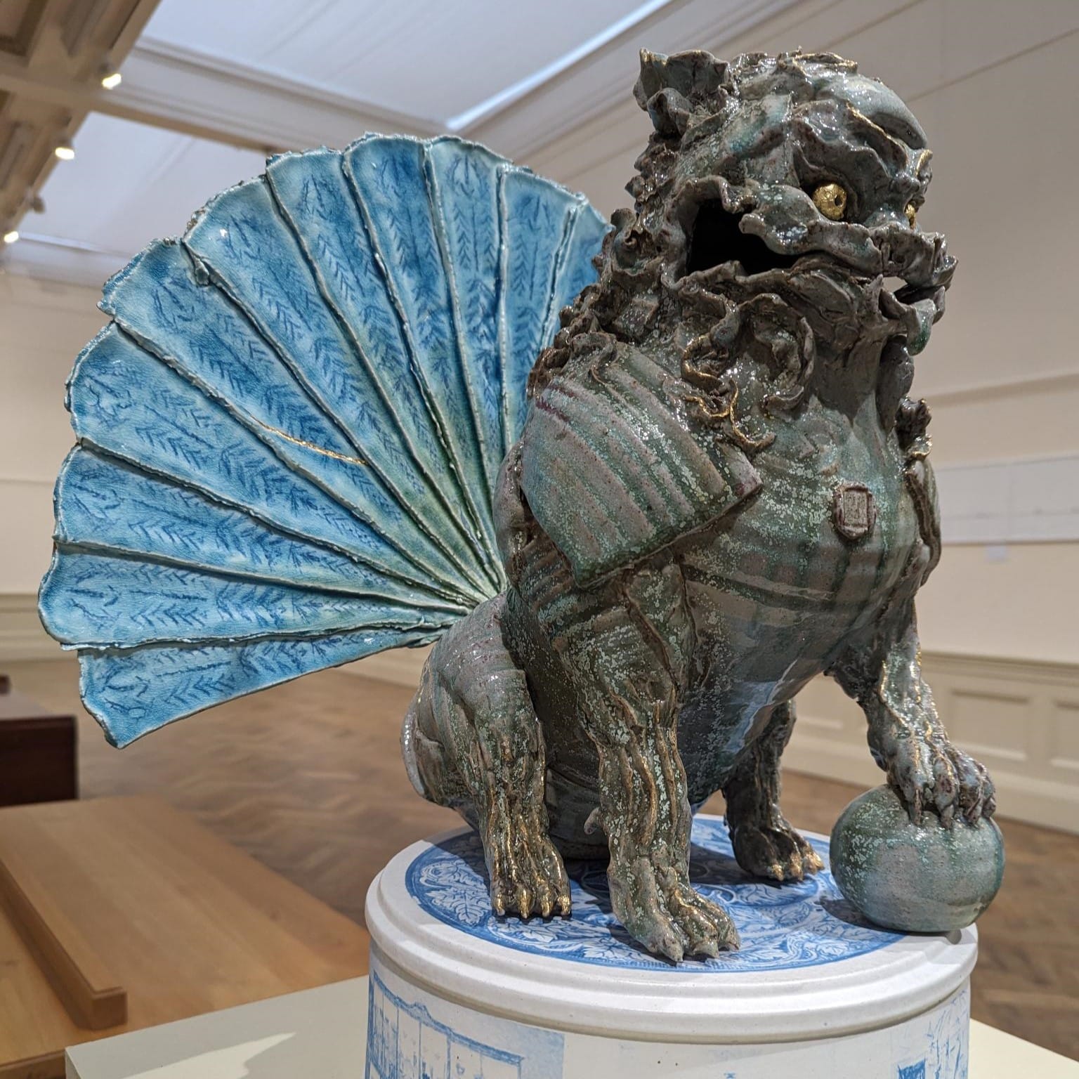 a ceramic Foo Dog made by artist Jacob Chan. A traditional Chinese design but with a pale blue fan as a tail.