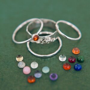 photograph of silver rings and coloured stones against a green background