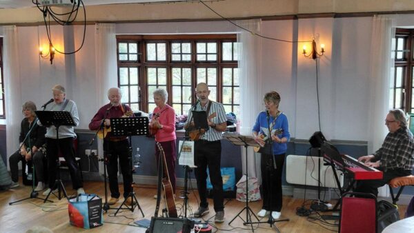 A photography of two men and 2 women holding instruments singing