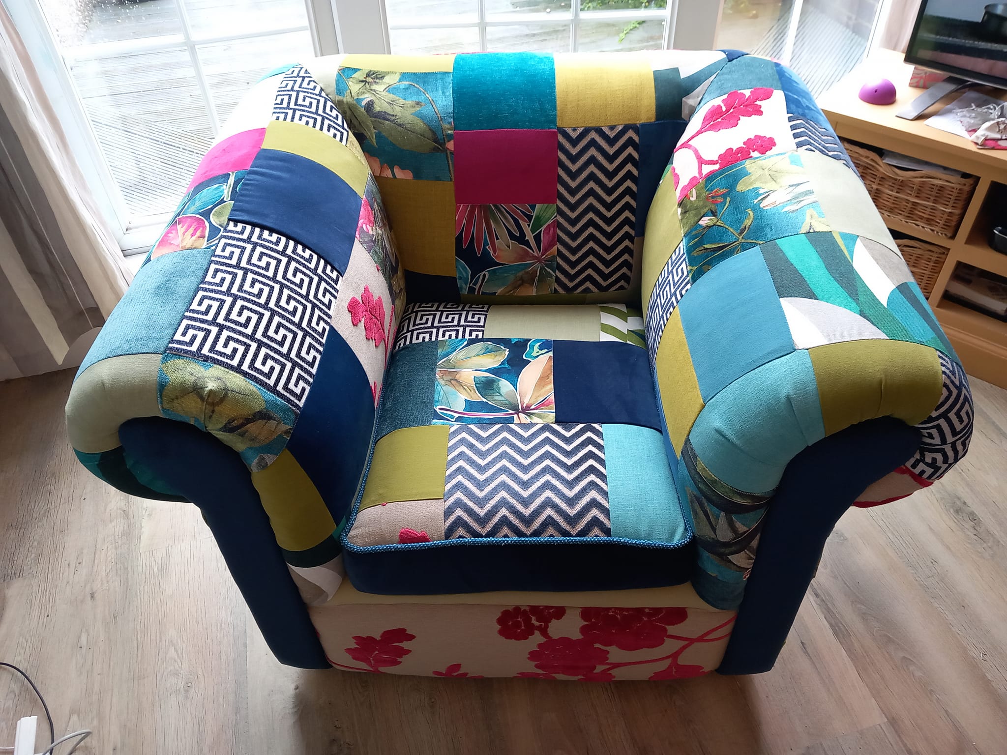 Photograph of a high-armed armchair upholstered in a colourful patchwork of mixed fabrics